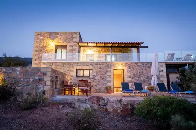 a stone house with chairs and a table at Blue Pearl Villa in AmigdhalokeFálion