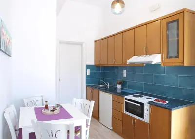 a kitchen with a table and a blue tile wall at Almiris Seaside Apartments in Almirida
