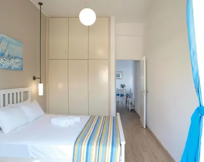 a bedroom with a white bed with a striped blanket at Almiris Seaside Apartments in Almirida