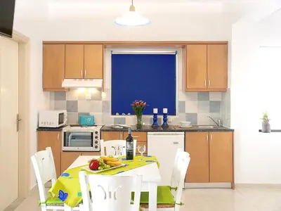 a kitchen with a table and chairs in a room at Almiris Seaside Apartments in Almirida