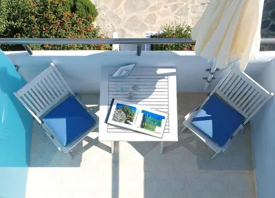 two chairs and an umbrella on a patio at Almiris Seaside Apartments in Almirida