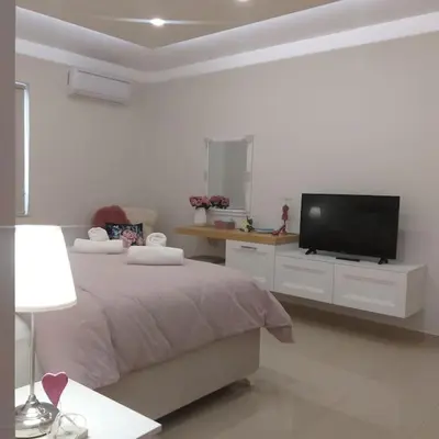 a white bedroom with a bed and a flat screen tv at Luxury apartment in the heart of the city in Chania Town