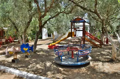 a playground with a slide in a park with trees at Camping Chania in Kato Daratso