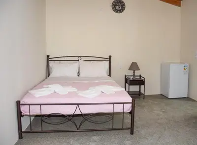 a bedroom with a bed with pink sheets and a refrigerator at Camping Chania in Kato Daratso