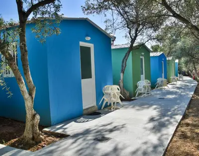 a row of blue and green buildings with chairs at Camping Chania in Kato Daratso