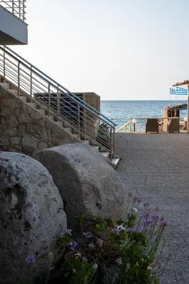 a staircase with rocks and flowers next to the ocean at Celeste Junior Suite on the Beach in Agia Marina Nea Kydonias