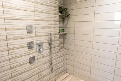 a bathroom with a shower with wooden tiles at Celeste Junior Suite on the Beach in Agia Marina Nea Kydonias