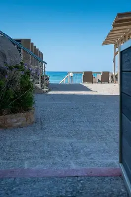 a sidewalk next to a beach with the ocean at Celeste Junior Suite on the Beach in Agia Marina Nea Kydonias