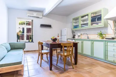 a kitchen with green cabinets and a table and chairs at Casa Ari - Venetian Port in Chania Town