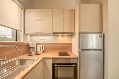 a kitchen with white cabinets and a stainless steel refrigerator at Koutris Apartment 2 in Falasarna