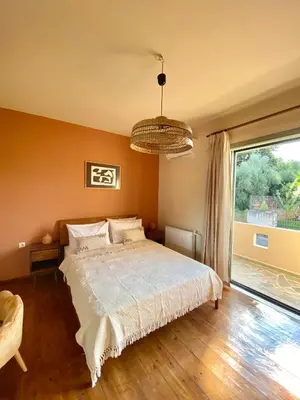 a bedroom with a bed and a large window at The Leaf House in Varípetron