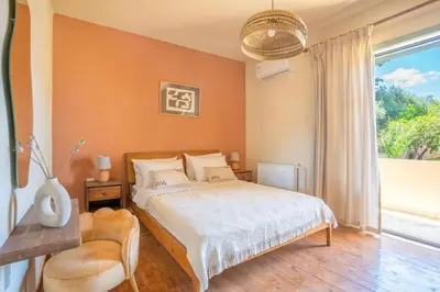 a bedroom with a bed and a large window at The Leaf House in Varípetron