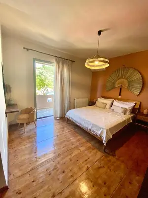 a bedroom with a bed and a large window at The Leaf House in Varípetron