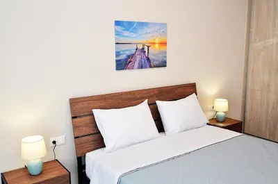 a bedroom with a bed with white sheets and two lamps at eleftheria's apartment in Chania Town