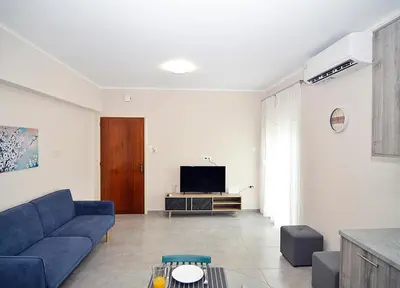 a living room with a blue couch and a tv at eleftheria's apartment in Chania Town