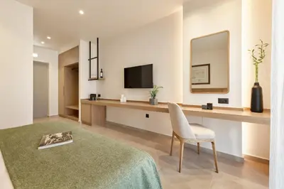 a room with a desk with a chair and a television at Inea Sole Boutique Hotel in Kato Daratso