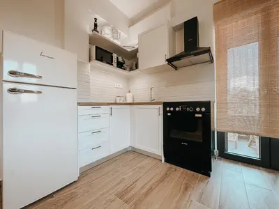 a kitchen with white cabinets and a black refrigerator at Stella's Boho Retreat in Palaiochóra