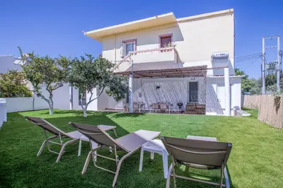 a group of chairs and tables on a lawn in front of a house at Kalyves Pearl apartments by the sea in Kalyves