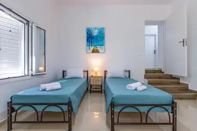 two twin beds in a room with a staircase at Kalyves Pearl apartments by the sea in Kalyves