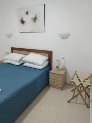 a bedroom with a blue bed and a wooden night stand at Kalyves Pearl apartments by the sea in Kalyves
