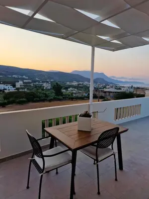 a wooden table and chairs on a balcony with an umbrella at S n G/ Best view apartment in Kissamos