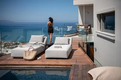 a woman standing on a balcony looking out at the ocean at Alectrona Living Crete, Villa Ãcro in Plataniás