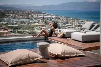 a woman sitting on the edge of a swimming pool at Alectrona Living Crete, Villa Ãcro in Plataniás