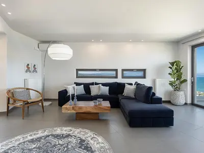 a living room with a blue couch and a table at Alectrona Living Crete, Villa Ãcro in Plataniás