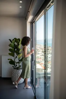 a woman looking out the window of a building at Alectrona Living Crete, Villa Ãcro in Plataniás