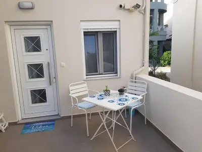 a table and chairs on a balcony with a door at happy travelers studio free parking in Chania Town