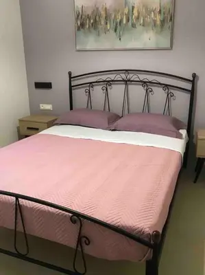 a bed with pink sheets and purple pillows in a bedroom at Anastasia’s Home in Chania Town