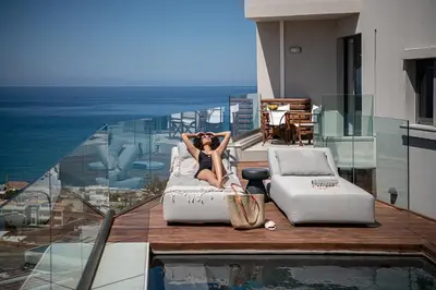 a woman laying on a couch on a balcony at Alectrona Living Crete, Apartment Olīvea in Plataniás