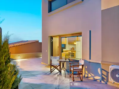 a patio with two chairs and a table on a building at Alectrona Living Crete, Apartment Olīvea in Plataniás