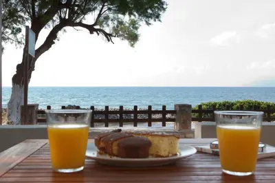 a table with a plate of food and orange juice at Horizonte Seafront Suites in Kissamos