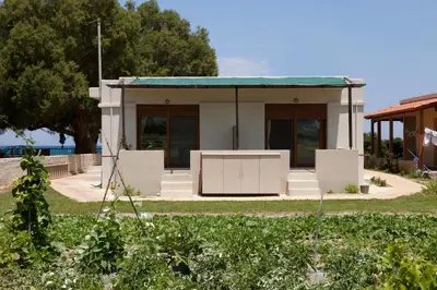 a small white house with a green roof at Horizonte Seafront Suites in Kissamos