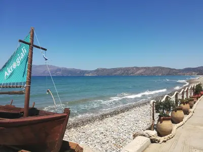 a beach with a row of potted plants and the ocean at Horizonte Seafront Suites in Kissamos