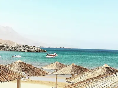 a group of straw umbrellas on a beach at Horizonte Seafront Suites in Kissamos