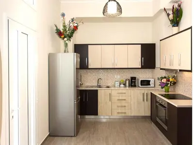a kitchen with a stainless steel refrigerator with flowers on top at Green Orange Villa near Platanias in Chania Town