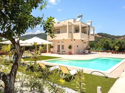 a villa with a swimming pool in front of a house at Green Orange Villa near Platanias in Chania Town