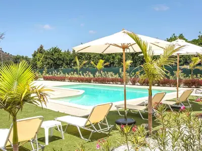a group of chairs and an umbrella next to a swimming pool at Green Orange Villa near Platanias in Chania Town