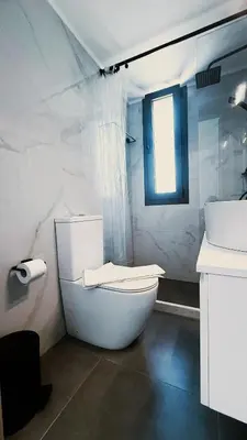 a white bathroom with a toilet and a window at Ek Ornelakis, Luxury Country House with Jacuzzi in Chania Town