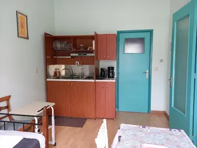 a kitchen with wooden cabinets and a blue door at The blackbird's nest in Chania Town