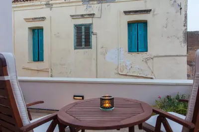 a candle on a table on a balcony with a building at Pleiades Apartments in Chania Town