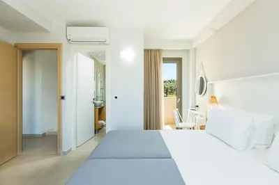 a white bedroom with a large bed and a bathroom at Estel Residences in Chania Town