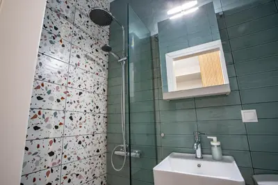 a bathroom with a sink and a shower with a mirror at Little gem by the sea in Chania Town