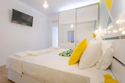 a white bedroom with a large bed with yellow pillows at Oasis by the sea in Chania Town