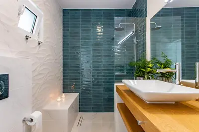 a bathroom with a white sink and green tiles at Oasis by the sea in Chania Town