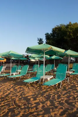 a group of chairs and umbrellas on a beach at Papidakis Studios in Agia Marina Nea Kydonias