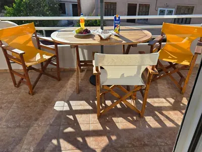 a wooden table and chairs on a balcony with a table and chairsktop at Nora Apartment in Almyrida in Chania Town