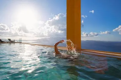 a person in a swimming pool with the ocean in the background at Seafront Ravdoucha Epavlis Athina Villa - Pool, Gym, Sauna, Private Parking, WiFi in Ravdhoúkha